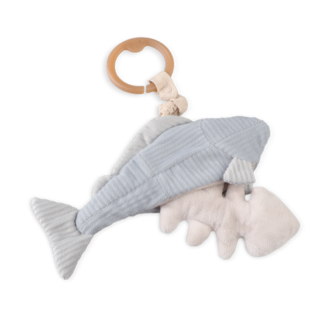 A blue and cream plush whale baby rattle hangs from a wooden teething ring.