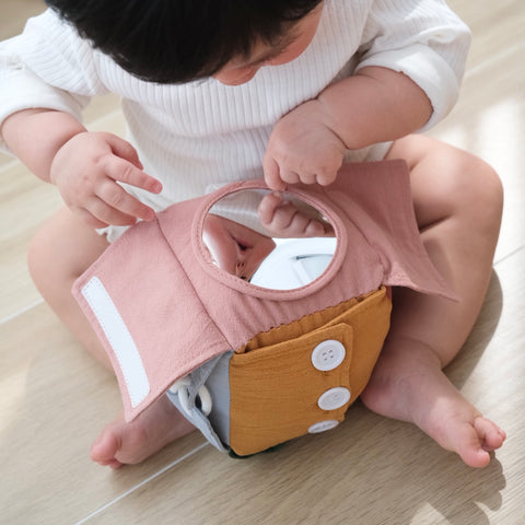 Baby explores reflection in soft, fabric activity cube mirror.