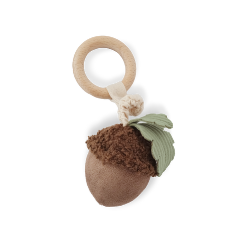 A brown plush acorn baby rattle with a fuzzy cap and soft green leaf hangs from a natural wooden teething ring.