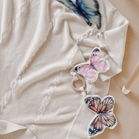 Butterfly mobile rests on a cream knit baby blanket.