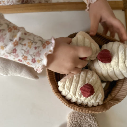 Child picks up a soft, corduroy, plush toy cupcake from a matching basket.