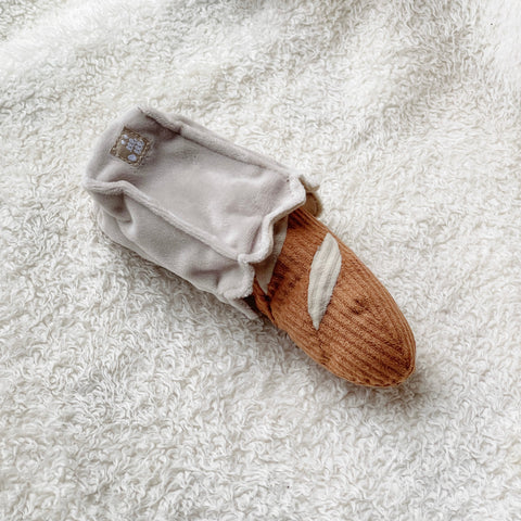 Plush baguette toy emerges from a soft, white bag.