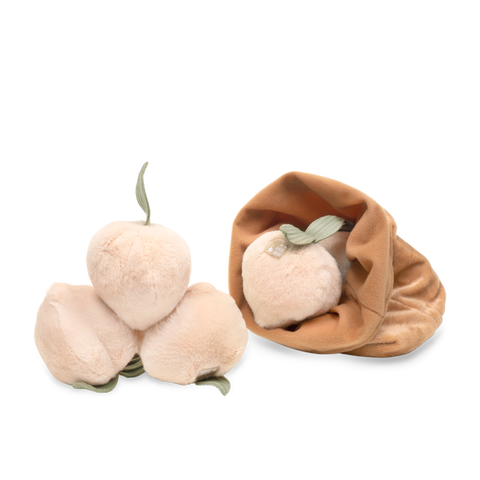 Three fuzzy peach plush toys show soft, peach-colored fabric and green felt leaves. One peach rests in a matching tan, velvety pouch.
